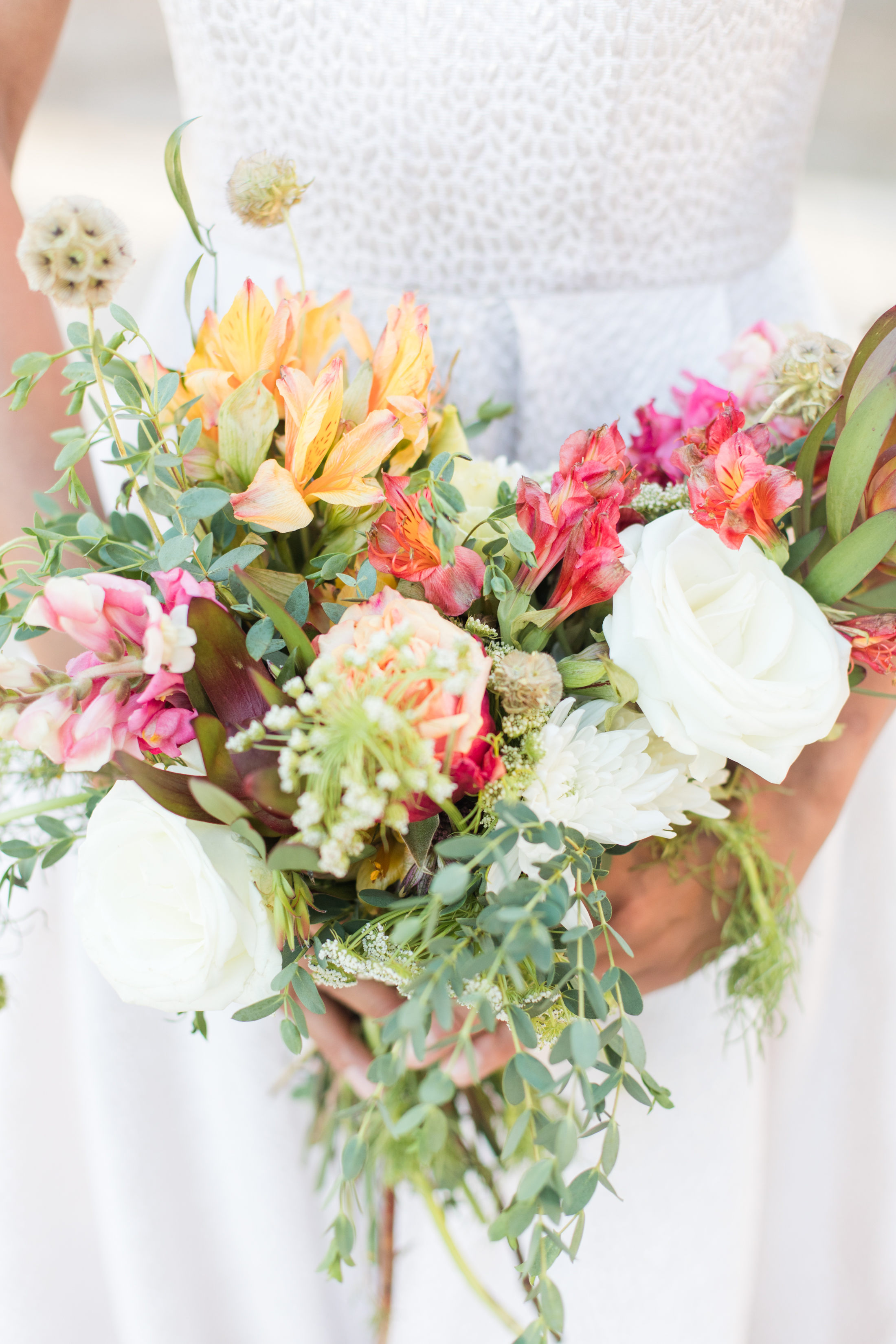 A bride holding a colorful boho bouquet
