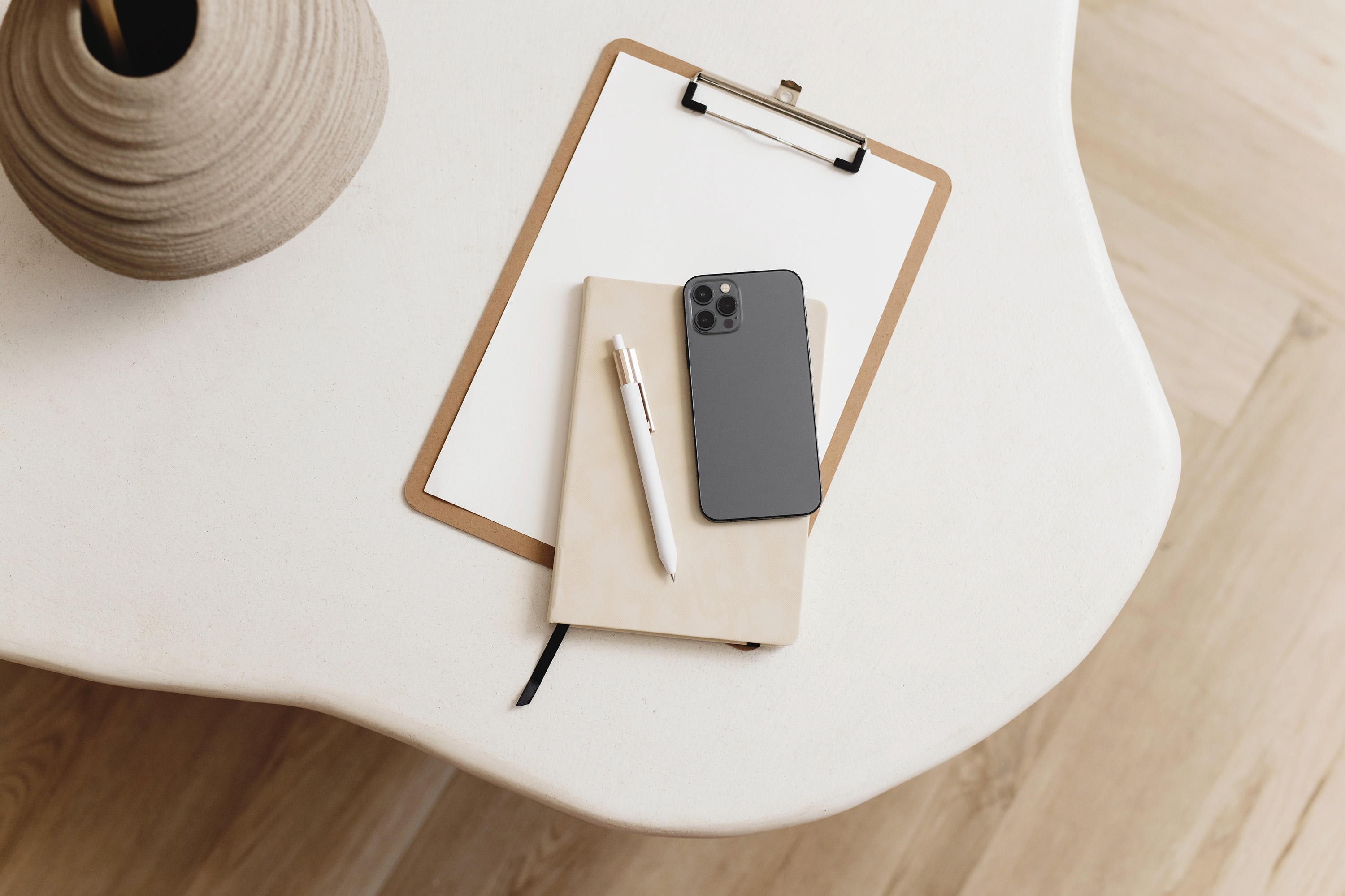 An organized desk with notebook, clipboard and phone